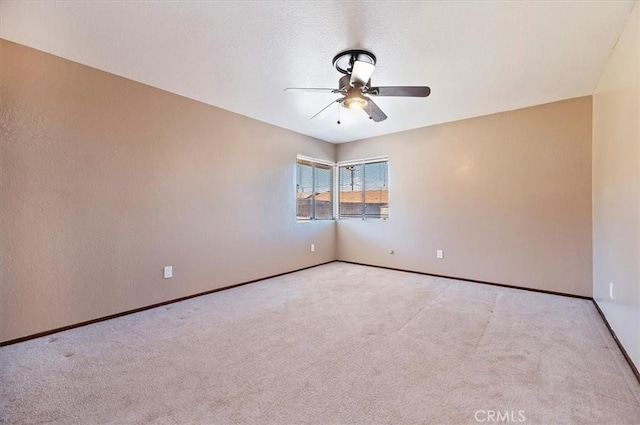 carpeted spare room featuring ceiling fan, baseboards, and a textured ceiling