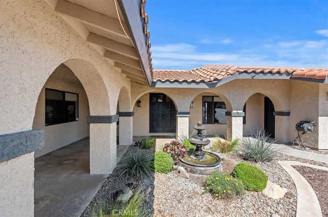 property entrance featuring a tile roof and stucco siding