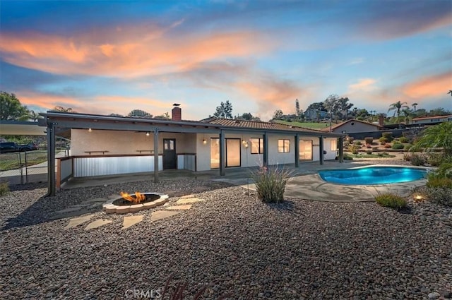 view of front of house featuring an outdoor fire pit, an outdoor pool, a chimney, fence, and a patio area