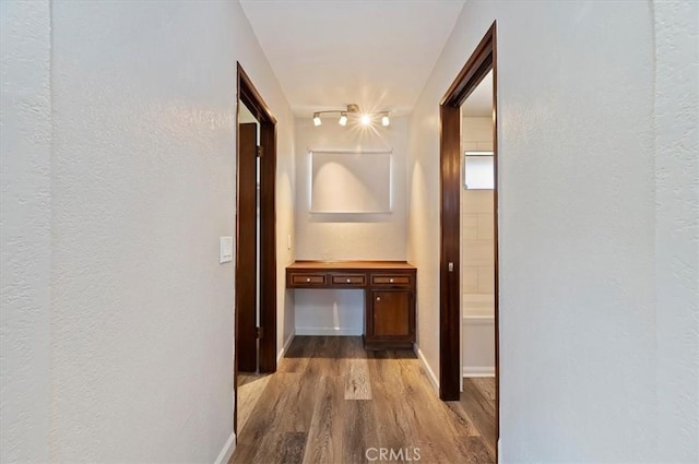 corridor featuring baseboards and wood finished floors