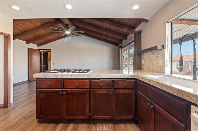 kitchen with vaulted ceiling with beams, white gas stovetop, a peninsula, a sink, and open shelves