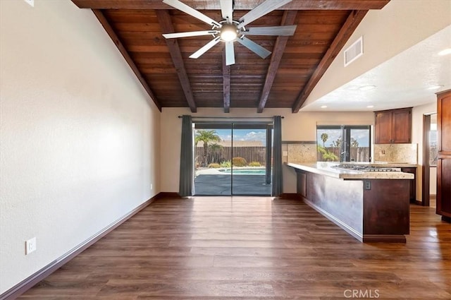 kitchen featuring dark wood-type flooring, visible vents, vaulted ceiling with beams, and a peninsula