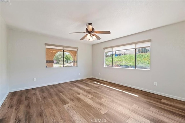 unfurnished room with wood finished floors, a wealth of natural light, and baseboards