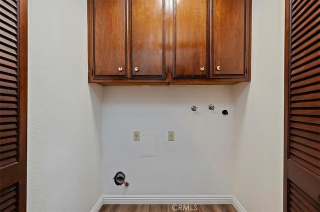 laundry room with cabinet space, gas dryer hookup, baseboards, and wood finished floors