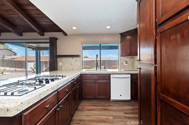 kitchen featuring white appliances, backsplash, a wealth of natural light, and a sink