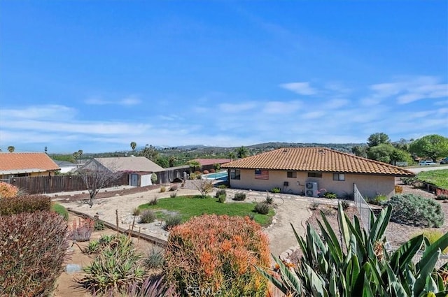 rear view of property with a tiled roof, fence, and stucco siding