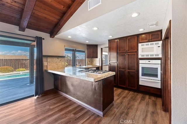 kitchen featuring white appliances, visible vents, dark wood finished floors, a peninsula, and a warming drawer