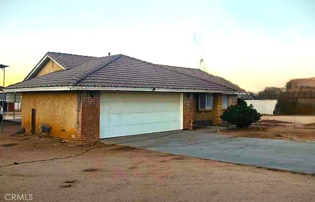 view of front of home with an attached garage, concrete driveway, and a tiled roof