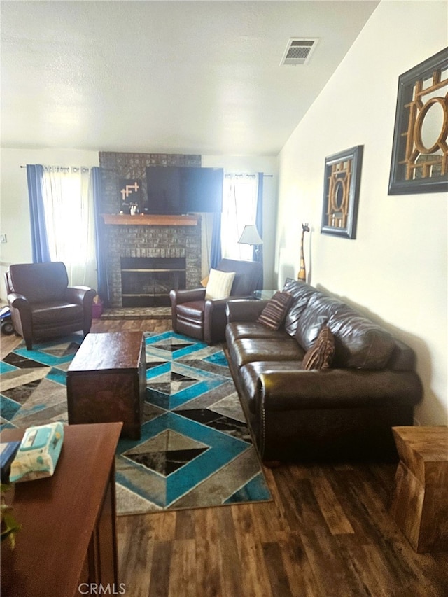 living area featuring a fireplace, wood finished floors, visible vents, and a healthy amount of sunlight