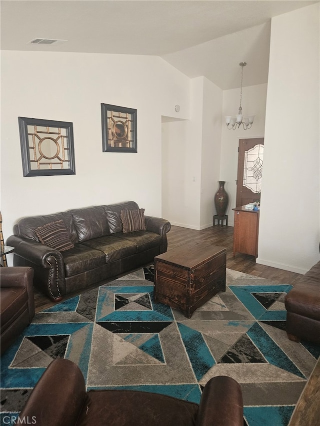 living area with baseboards, visible vents, wood finished floors, an inviting chandelier, and vaulted ceiling