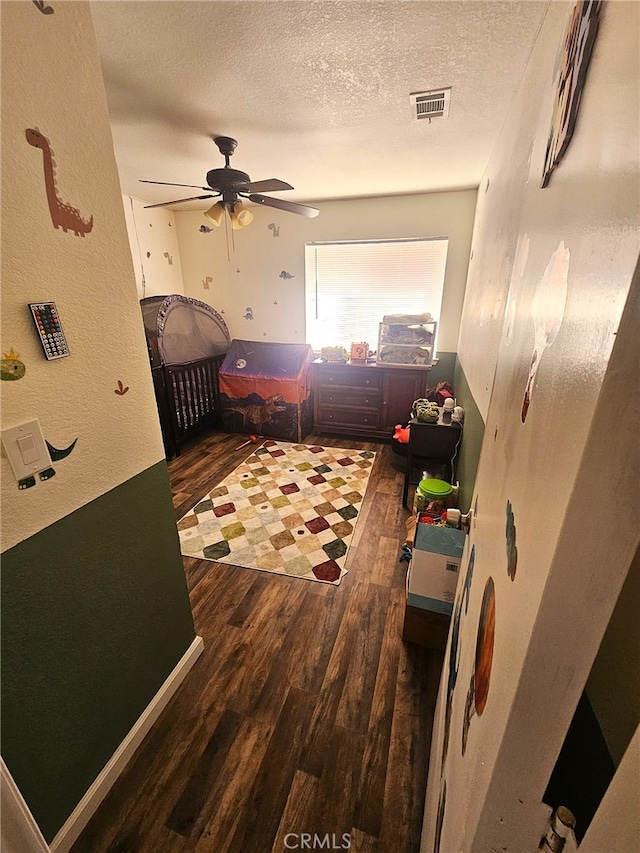 bedroom with visible vents, a ceiling fan, a textured wall, wood finished floors, and a textured ceiling