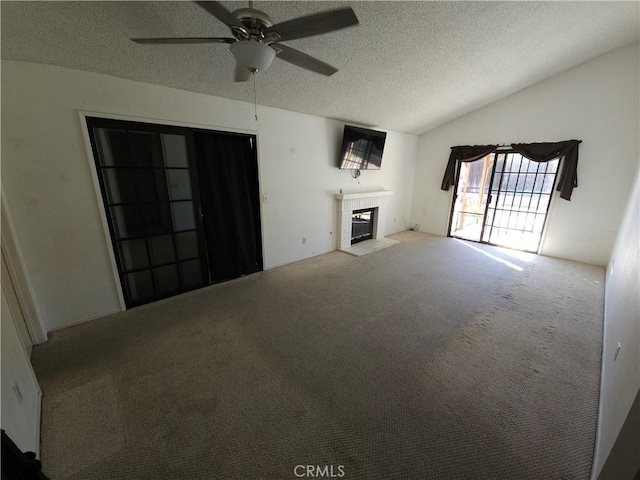 unfurnished living room featuring carpet, a fireplace, vaulted ceiling, and a textured ceiling