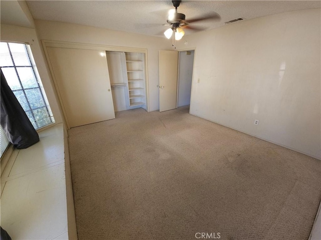 unfurnished bedroom with a ceiling fan, a closet, visible vents, and light carpet