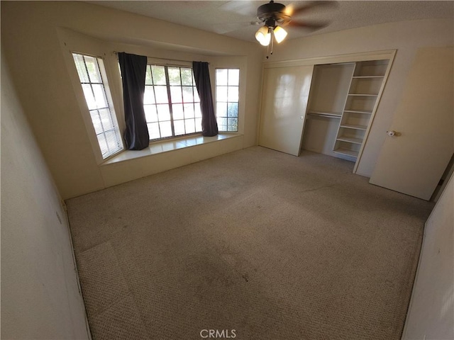 unfurnished bedroom with carpet floors, a closet, multiple windows, and a ceiling fan