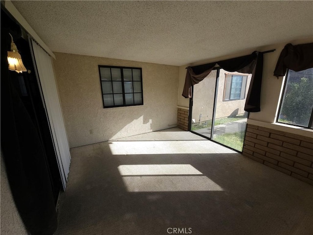 interior space with a textured ceiling, a textured wall, and carpet flooring