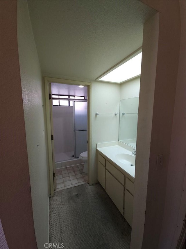 full bath with toilet, a stall shower, vanity, and tile patterned floors