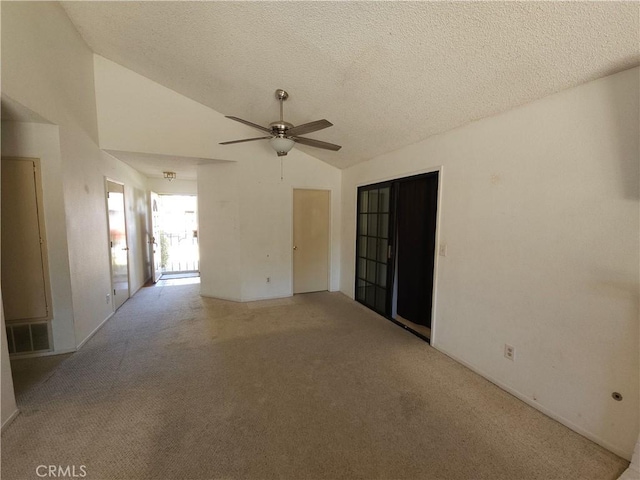 spare room with lofted ceiling, ceiling fan, a textured ceiling, light carpet, and visible vents