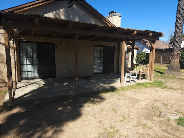 back of house featuring fence, a chimney, and a patio