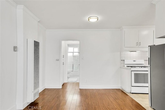 kitchen with white gas stove, a heating unit, freestanding refrigerator, ornamental molding, and light wood-style floors