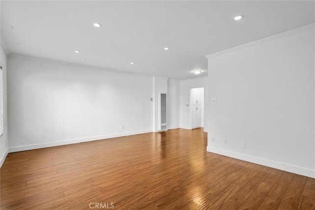 spare room with crown molding, recessed lighting, wood finished floors, and baseboards