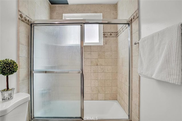 full bathroom featuring toilet and a tile shower