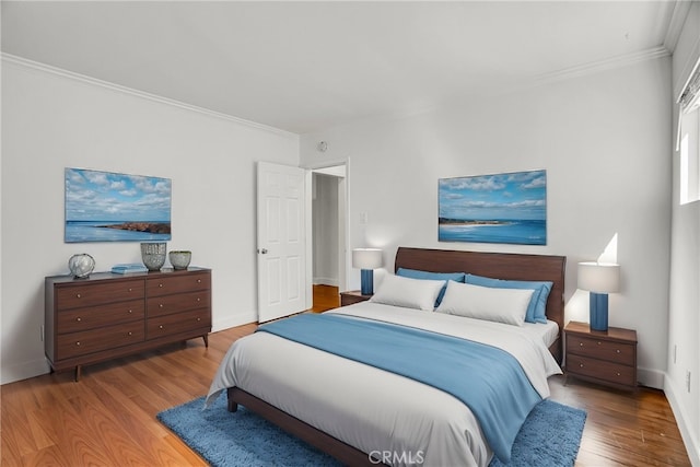 bedroom with ornamental molding, baseboards, and wood finished floors