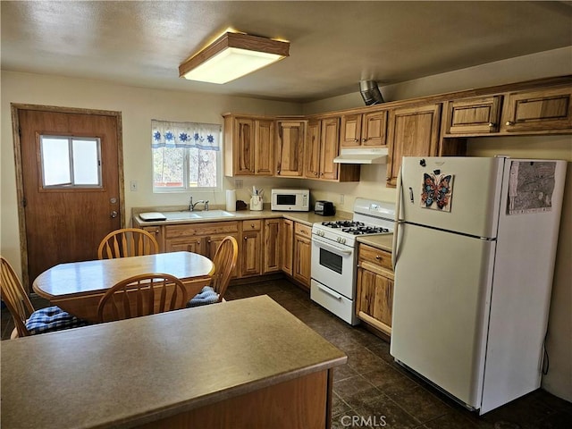 kitchen featuring under cabinet range hood, light countertops, brown cabinetry, white appliances, and a sink