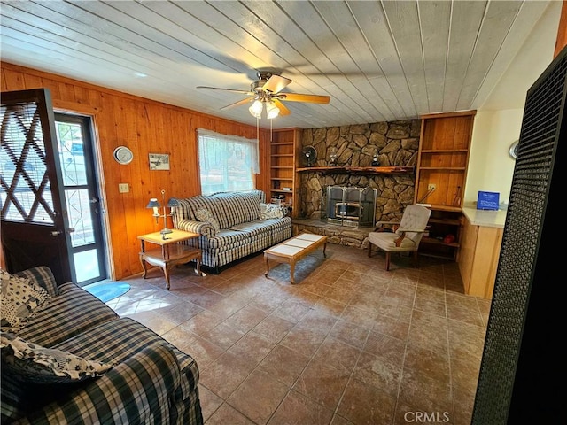 living room featuring wooden walls, built in shelves, wooden ceiling, and ceiling fan