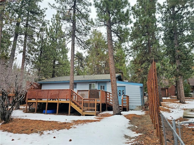 snow covered house featuring a deck and fence