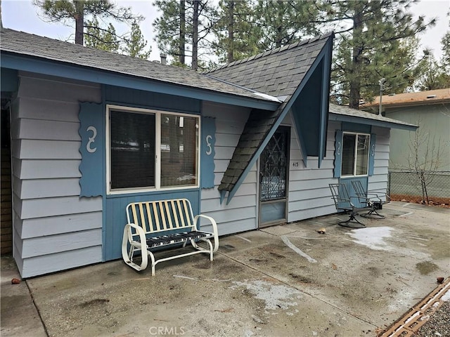 back of property with a patio, roof with shingles, and fence