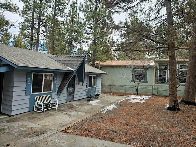 exterior space featuring a patio, fence, and roof with shingles