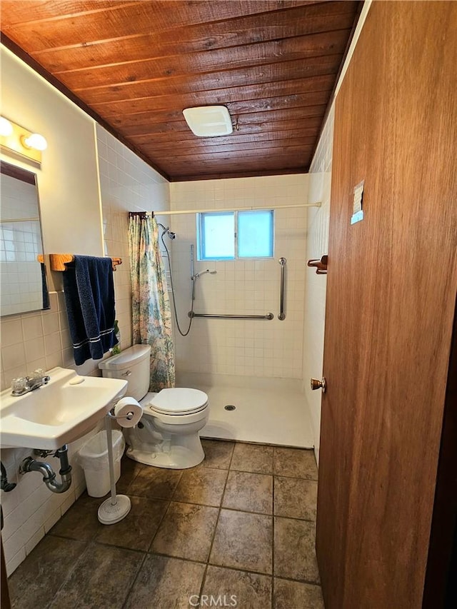 full bath with toilet, a sink, tile walls, a shower stall, and wood ceiling