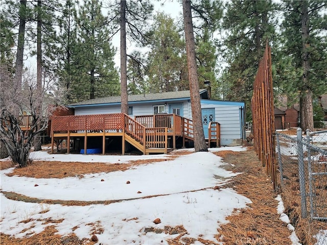 snow covered property featuring a deck and fence