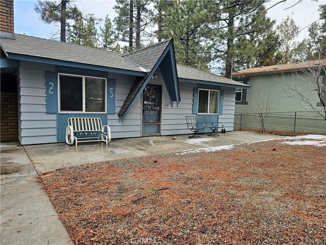 view of front of home featuring fence, roof with shingles, and a chimney