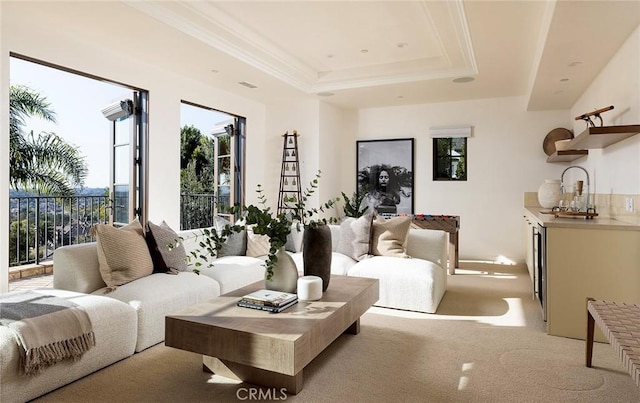 living room featuring light colored carpet, a tray ceiling, and ornamental molding