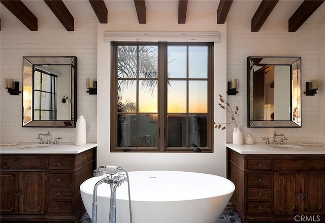 full bathroom with decorative backsplash, a soaking tub, two vanities, and a sink