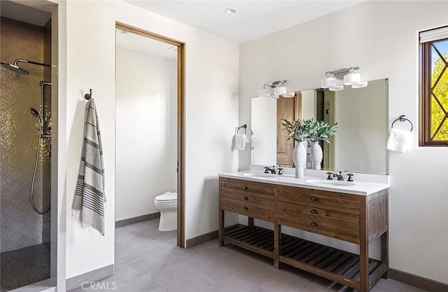 bathroom with double vanity, a walk in shower, toilet, and a sink