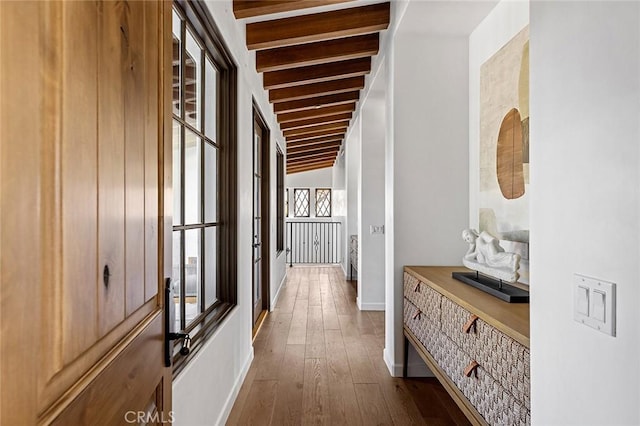 corridor featuring beam ceiling, dark wood-type flooring, and baseboards