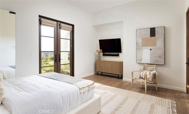 bedroom with wood finished floors, baseboards, and french doors