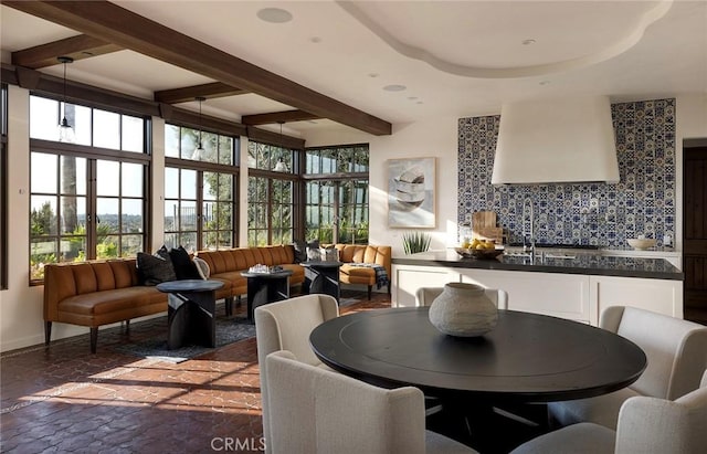 dining space featuring beamed ceiling, stone finish floor, and baseboards