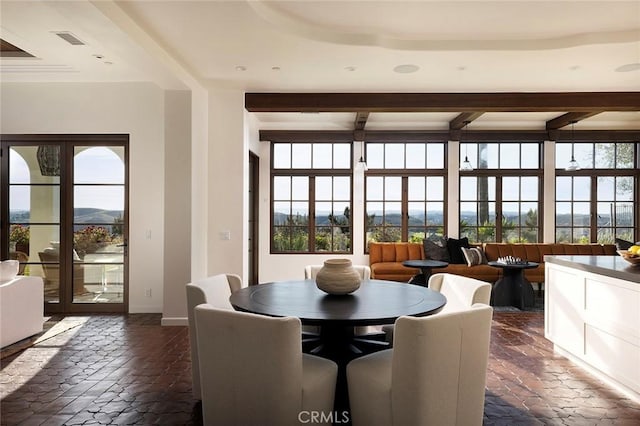 dining space with baseboards, plenty of natural light, beam ceiling, and visible vents