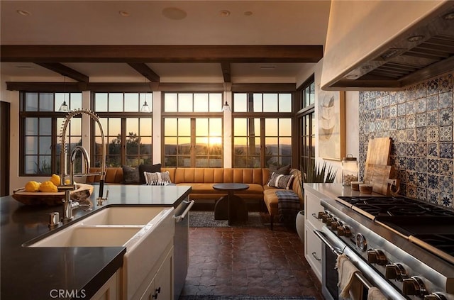 kitchen featuring ventilation hood, appliances with stainless steel finishes, stone tile flooring, white cabinets, and a sink