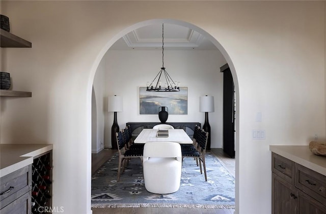 dining room featuring a raised ceiling, light wood-style flooring, crown molding, and arched walkways