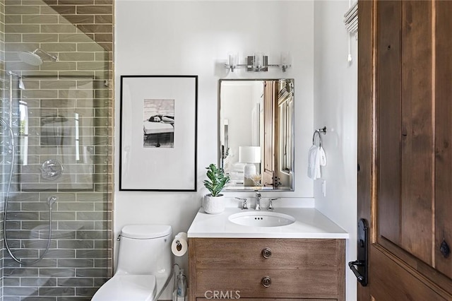 full bath featuring a tile shower, toilet, and vanity