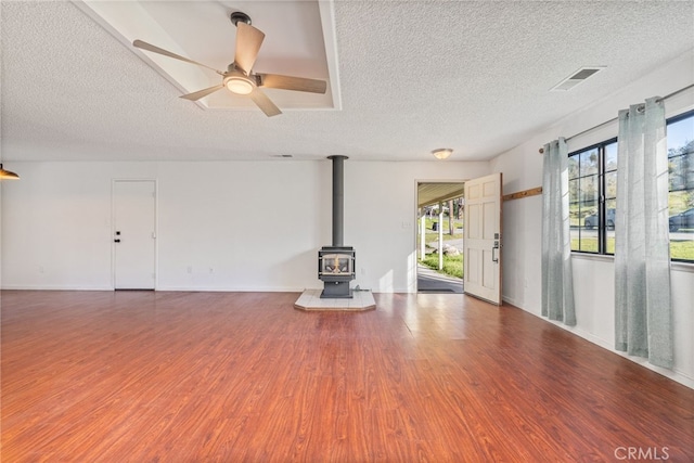 43317 Running Deer Ct, Coarsegold, CA 93614 - unfurnished living room with wood finished floors, a wood stove, a textured ceiling, a ceiling fan, and baseboards