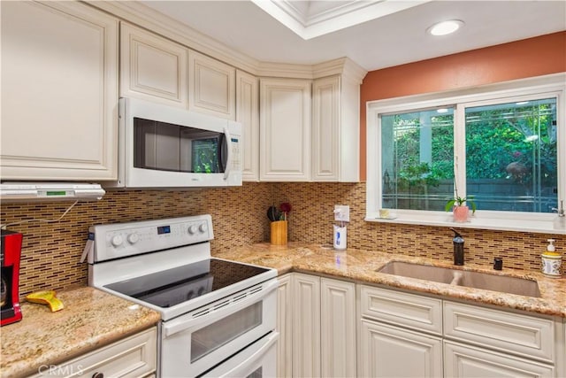 kitchen featuring light stone counters, tasteful backsplash, a sink, and white appliances