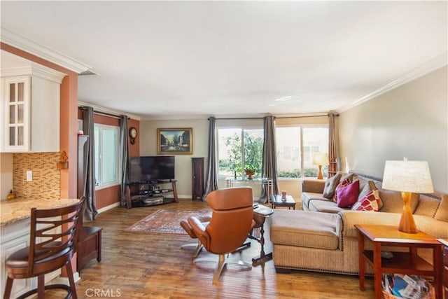 living area featuring ornamental molding, baseboards, and wood finished floors