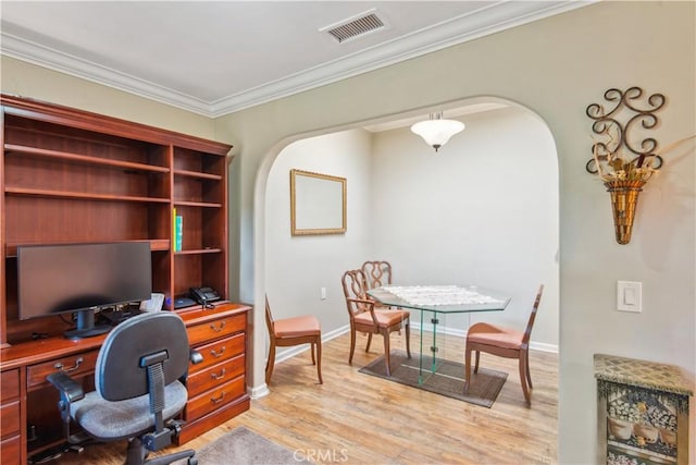 office featuring ornamental molding, light wood-type flooring, visible vents, arched walkways, and baseboards