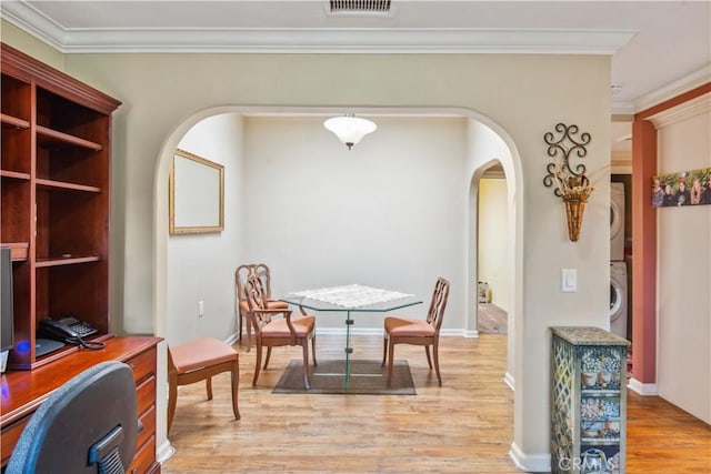 3001C Via Buena Vis Unit C, Laguna Woods, CA 92637 - dining space featuring stacked washing machine and dryer, arched walkways, light wood-style floors, crown molding, and baseboards