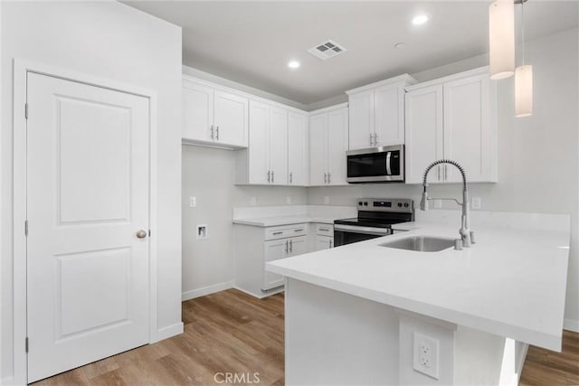 kitchen featuring stainless steel appliances, a peninsula, a sink, visible vents, and light countertops